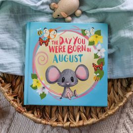 Front cover of book in a seagrass tray. Playful, illustrated mouse sat down surrounded by bees, butterflies and gladioli flowers.
