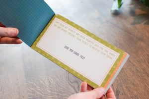 Hands holding a dog themed ticket book that says "this book of tickets has been created just for you. When you are ready, present your ticket to receive your treat. Love you loads, Tilly"