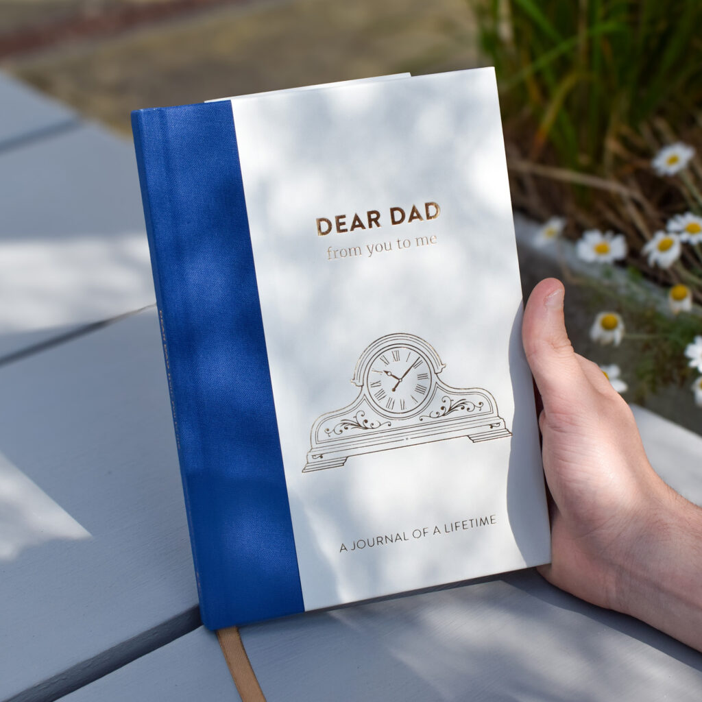 Holding Dear Dad Memory Journal in the sun, showing gold foil reflecting.