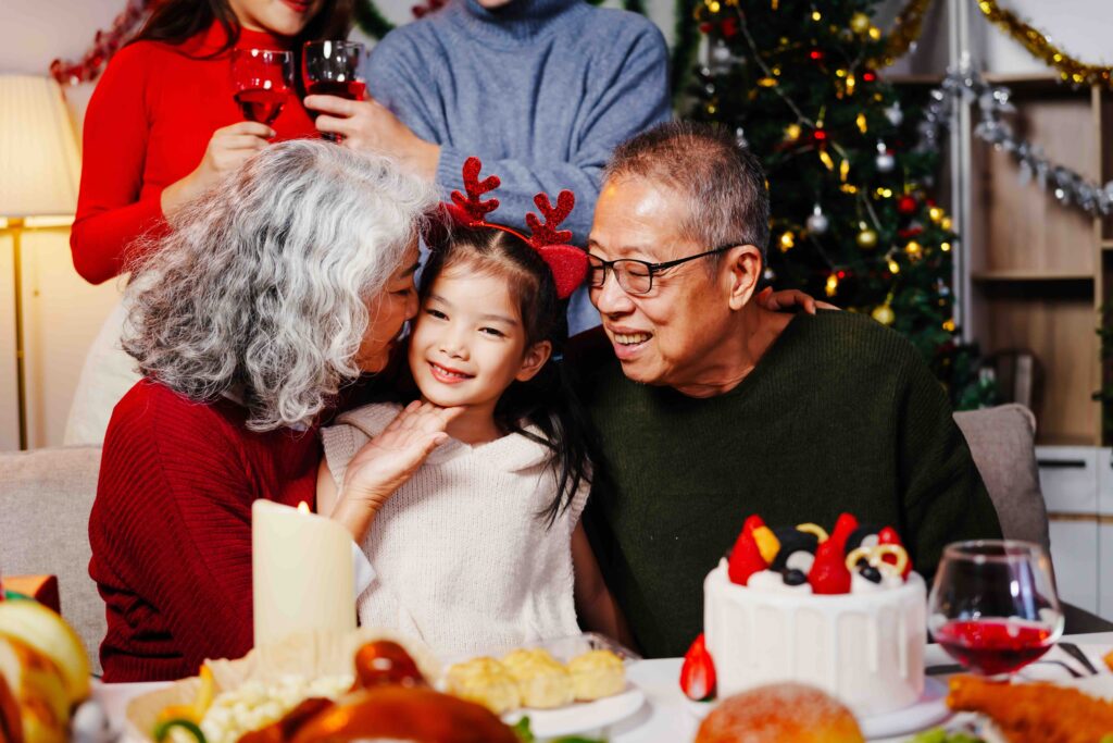 Grandparents with granddaughter around Christmas table.